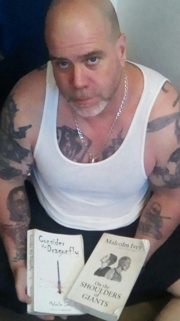 Me holding two of my novels in my lap, Consider the Dragonfly and On the Shoulders of Giants.