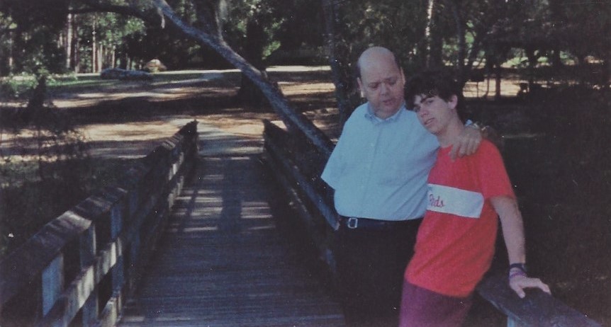 Dad talking to me as a teenager with his arm around my shoulders on a bridge in a park in Florida.